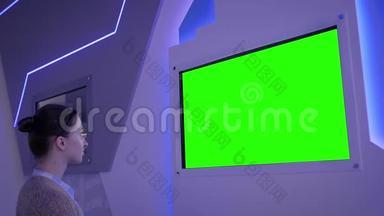 在展览中看到空白绿色展示墙的女人-绿色屏幕概念